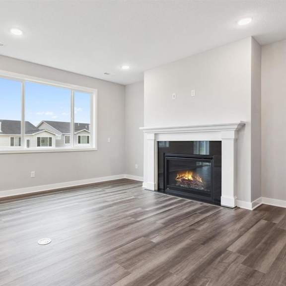 a spacious living room with a fireplace and a large window.