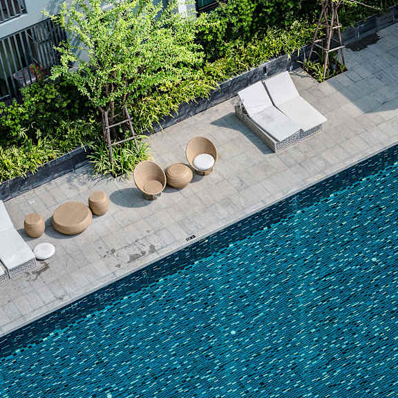 a hotel pool with chairs and umbrellas next to a swimming pool
