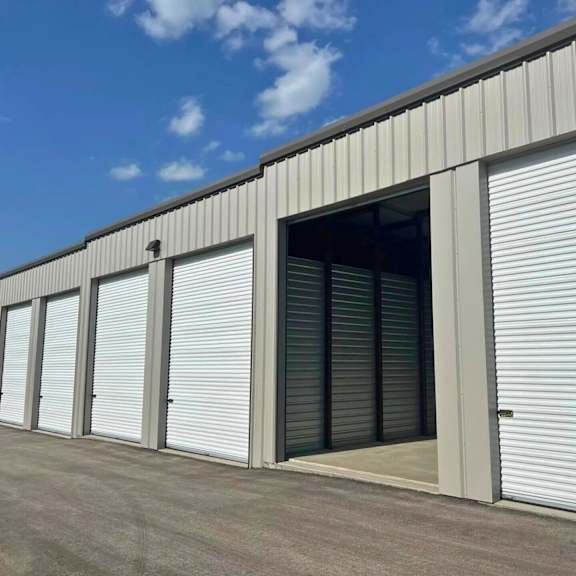 a series of white roller shutters are closed on a grey building.