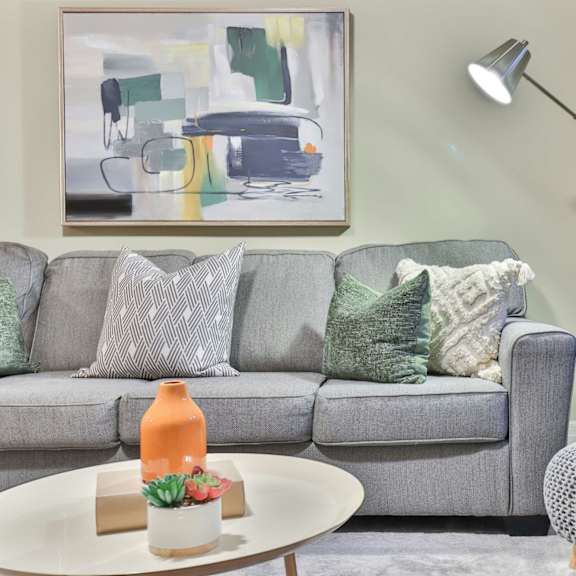 a grey couch with a grey and white pillow and a grey and white cushion on it.