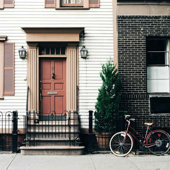 a bike parked in front of a white house with a red door
