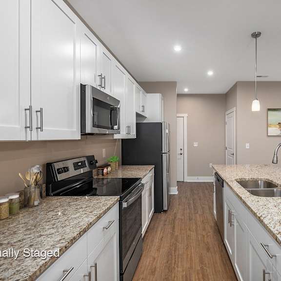 a large kitchen with granite counter tops and white cabinets