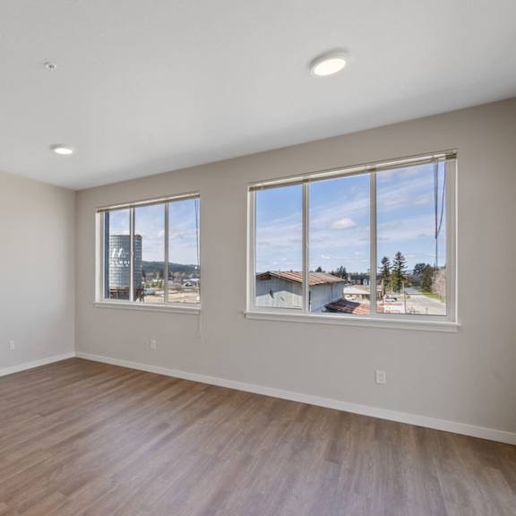a room with wooden flooring and two windows.
