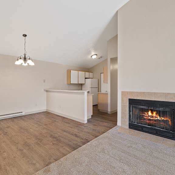 an empty living room with a fireplace and a kitchen