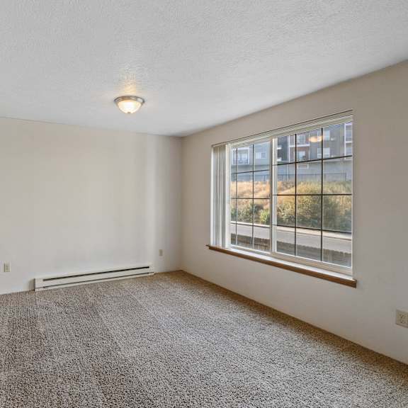 an empty living room with a large window and a kitchen