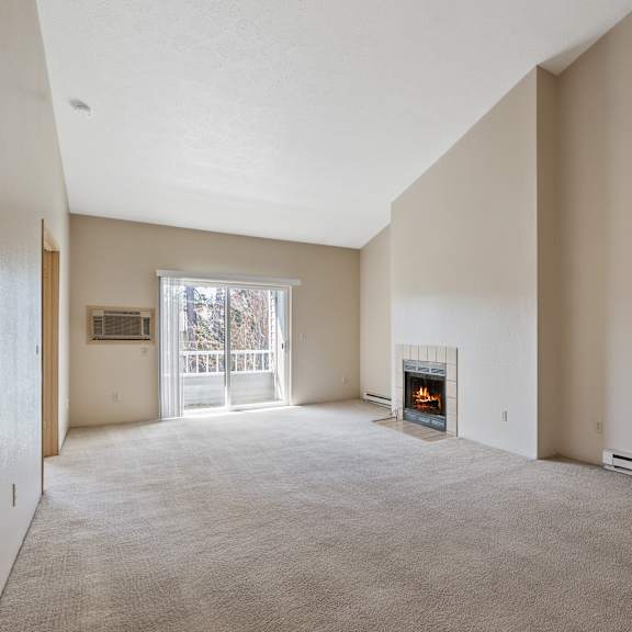 empty living room with carpet, fireplace, and sliding door to balcony.