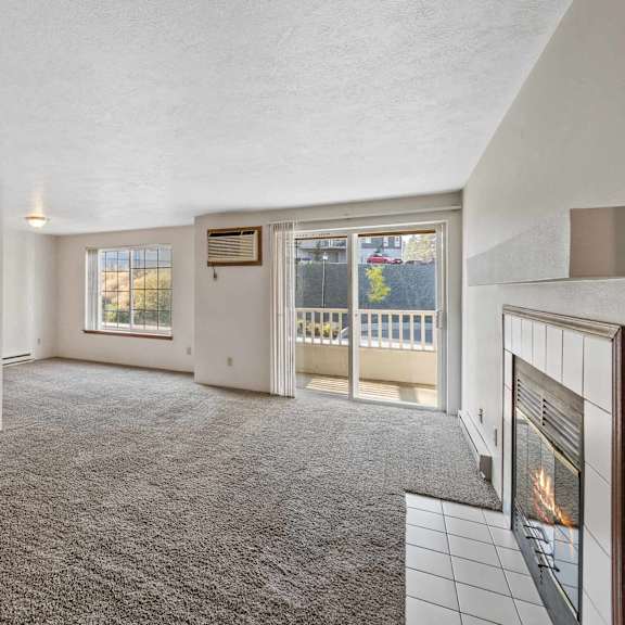 an empty living room with a fireplace and a door to a balcony