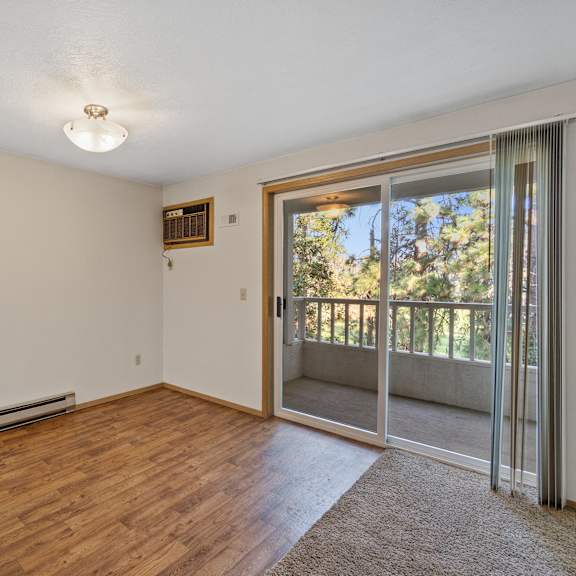 an empty living room with a sliding glass door to a balcony