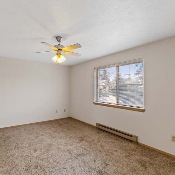 an empty living room with a ceiling fan and a window