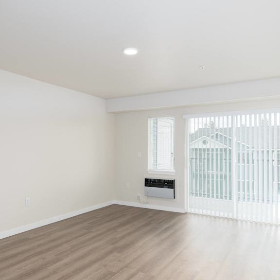 an empty living room with white walls and a window with a radiator and a door
