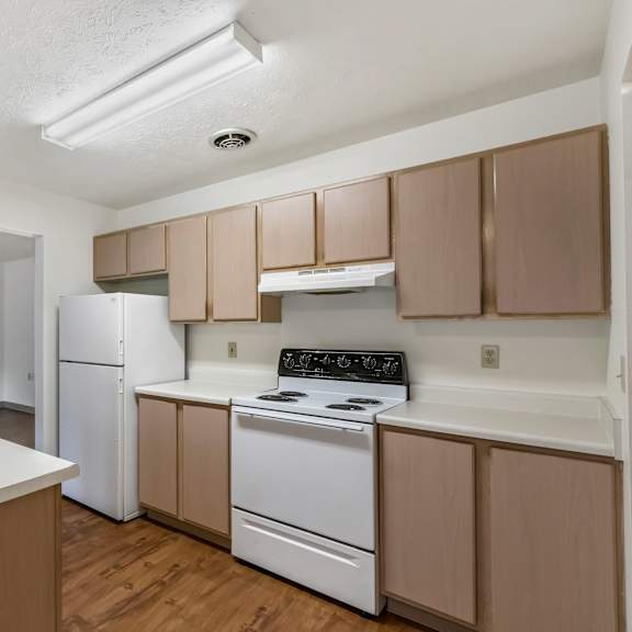 an empty kitchen with white appliances and wooden cabinets