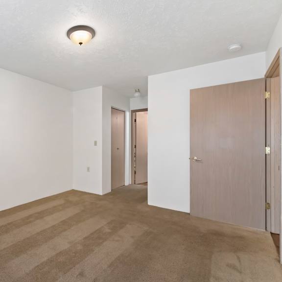 an empty living room with white walls and a door to a hallway