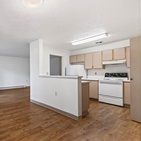 a kitchen with white appliances and wooden floors.