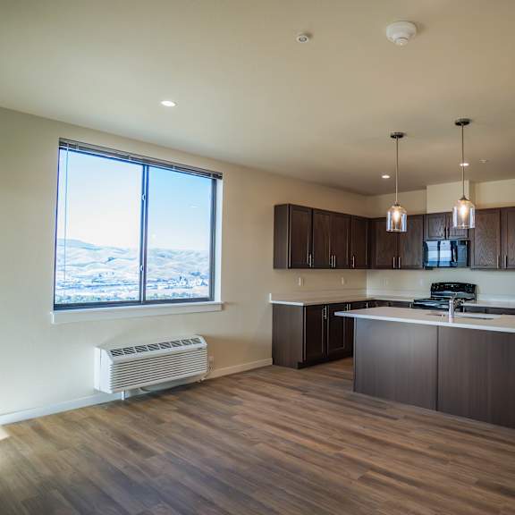 a kitchen with a large island and a window overlooking a mountainous landscape.
