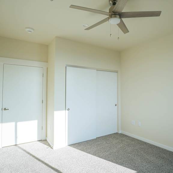 a room with a ceiling fan and two doors.