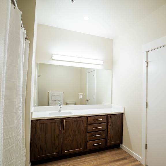 a bathroom with a white sink and brown cabinets.