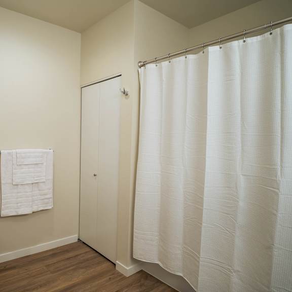 a white toilet sits next to a white shower curtain in a bathroom.