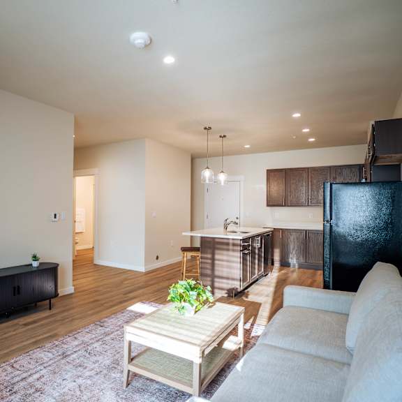 a living room with a green couch, a coffee table, and a television.
