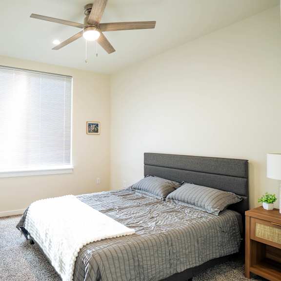 a bedroom with a bed, nightstand, and window.