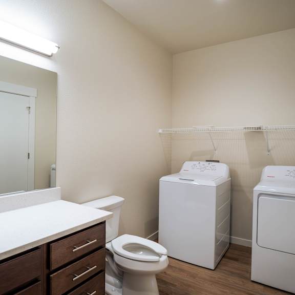 a small bathroom with a toilet, sink, and two washing machines.