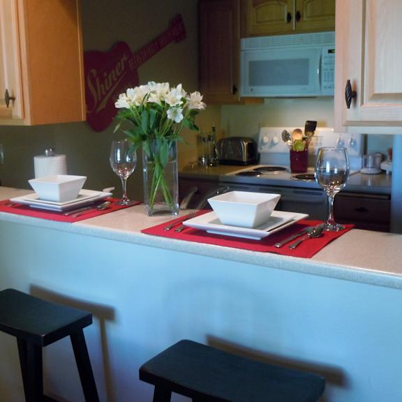a kitchen with a table set for two with a vase of flowers on it.