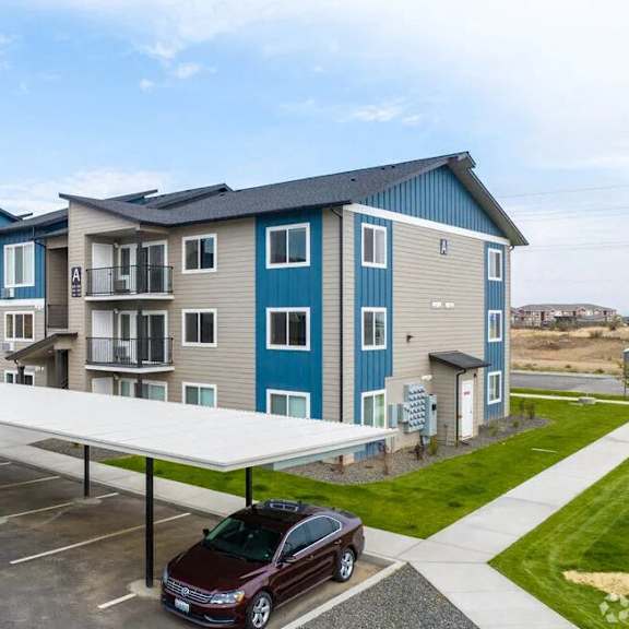 an apartment building with a car parked in a parking lot