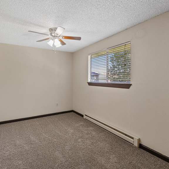empty bedroom with a ceiling fan and a window