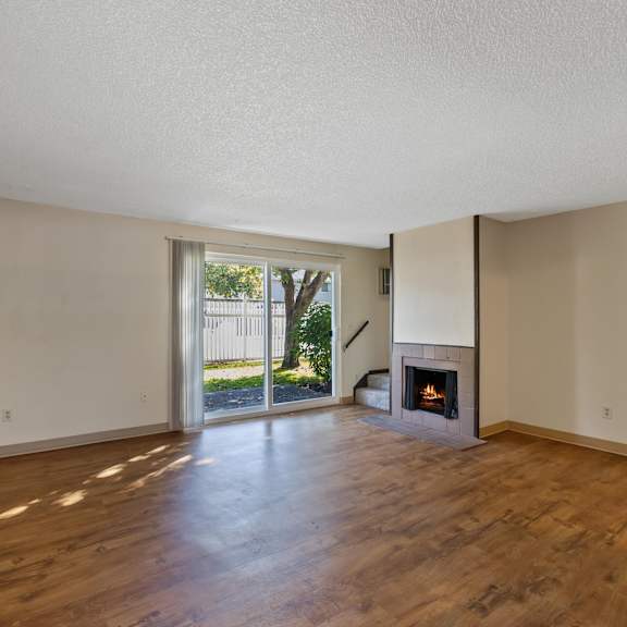 an empty living room with a fireplace and a sliding glass door