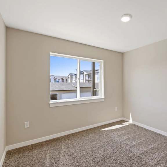 an empty bedroom with a window and carpet