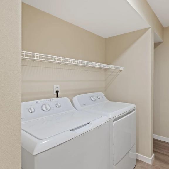 a white washer and dryer in a laundry room with a shelf above it
