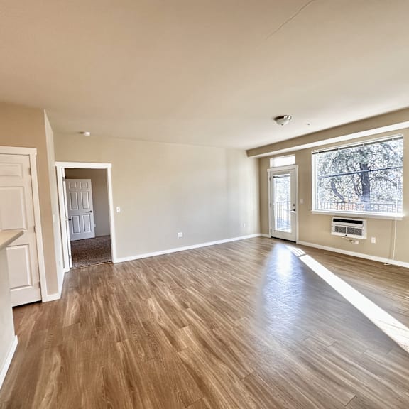 a room with wooden flooring and a window showing a tree outside.