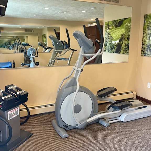 a gym with a treadmill, elliptical trainer and a mirror.