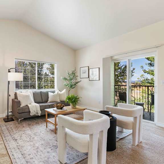 a living room with white furniture and a large window