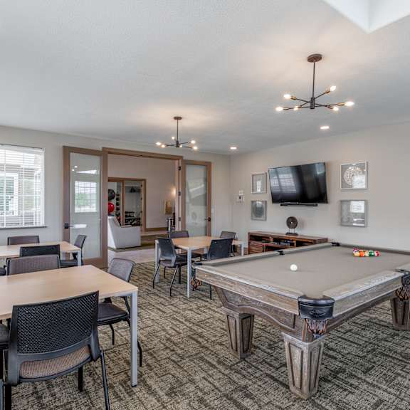 a community room with a pool table and chairs and a tv