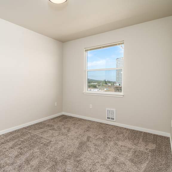 a room with a carpeted floor and a window showing a view of a cityscape.