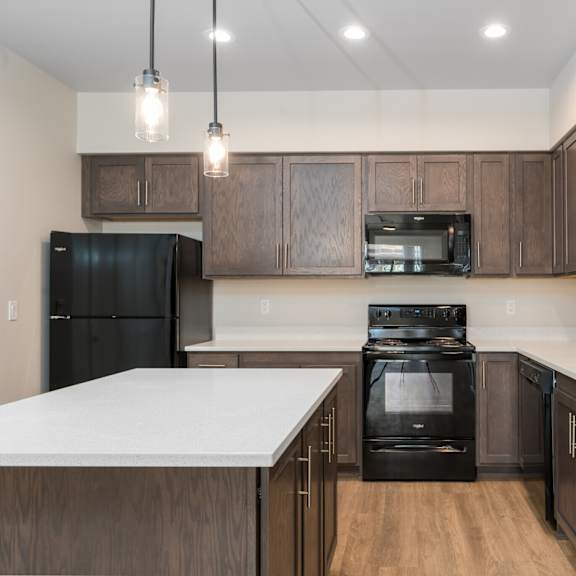 a modern kitchen with dark wood cabinets and black appliances.