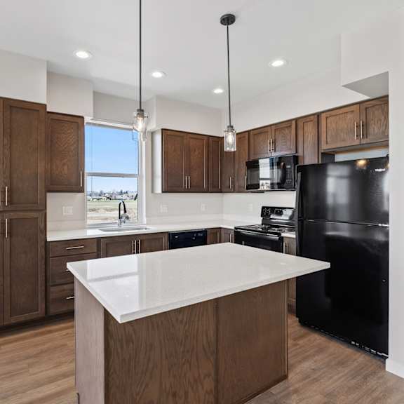 a modern kitchen with a black refrigerator and wooden cabinets.