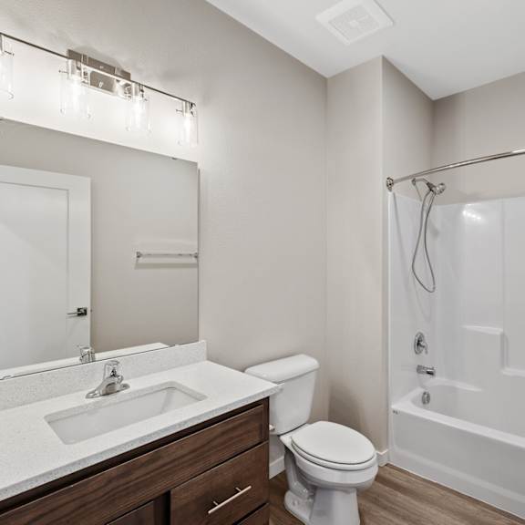 a white bathroom with a toilet, sink, and shower.