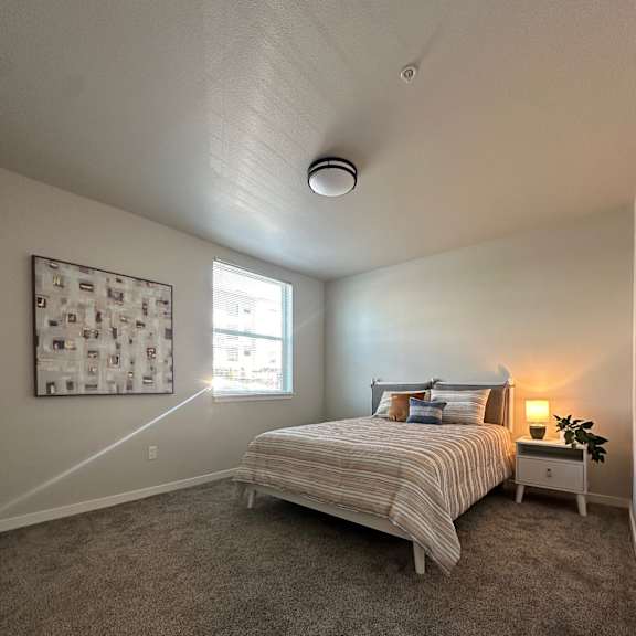 a bedroom with a bed, nightstand, and a window.