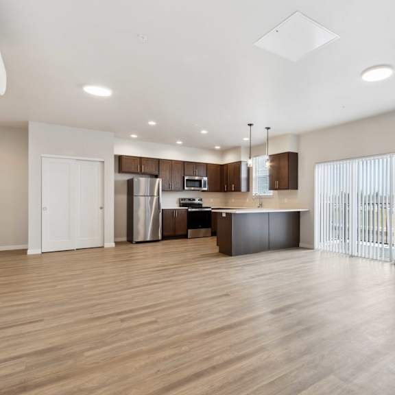 a spacious kitchen with wooden floors and white walls.