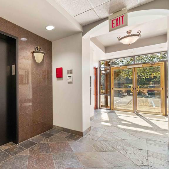 a door to a lobby with an exit sign and a glass door