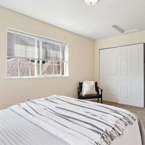 a bedroom with a bed, chair, and two doors.