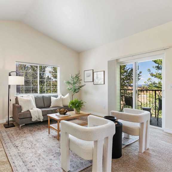 a living room with a grey couch, a wooden coffee table, and a large window.
