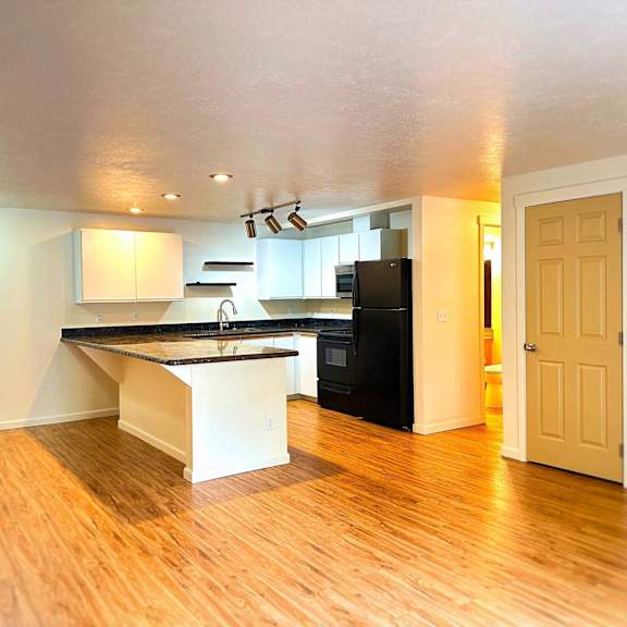 a kitchen with a black fridge and white cabinets.