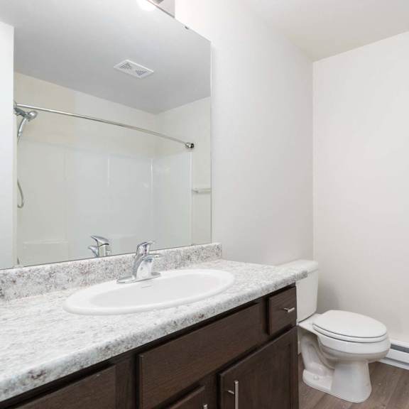 a white toilet sits in a bathroom next to a sink and a mirror.