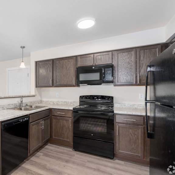 a kitchen with dark wood cabinets and black appliances.