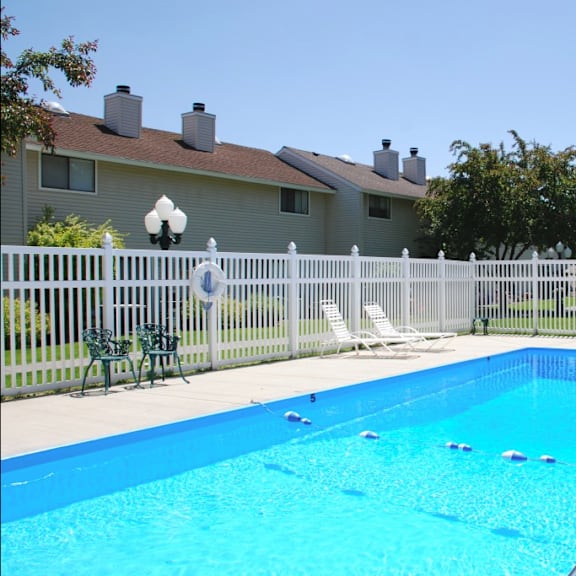 a swimming pool with a fence and a house in the background