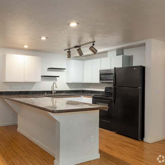 a kitchen with an island and a black refrigerator