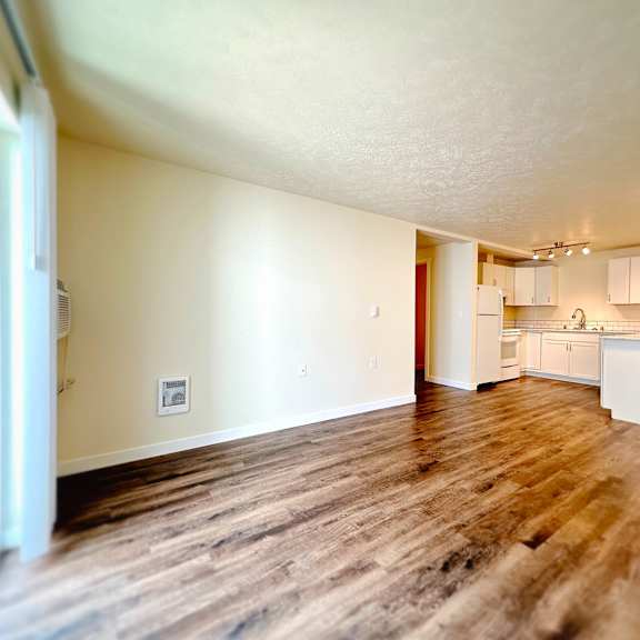 an empty living room and kitchen with wood floors