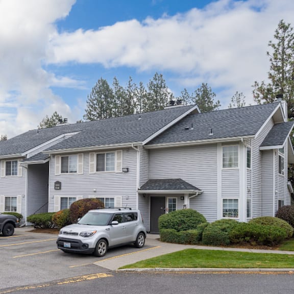 the view of an apartment building with cars parked in front of it